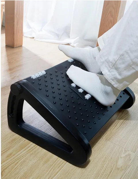 Pieds en chaussettes posés sur un repose-pieds noir à picots et rouleaux, sur un parquet