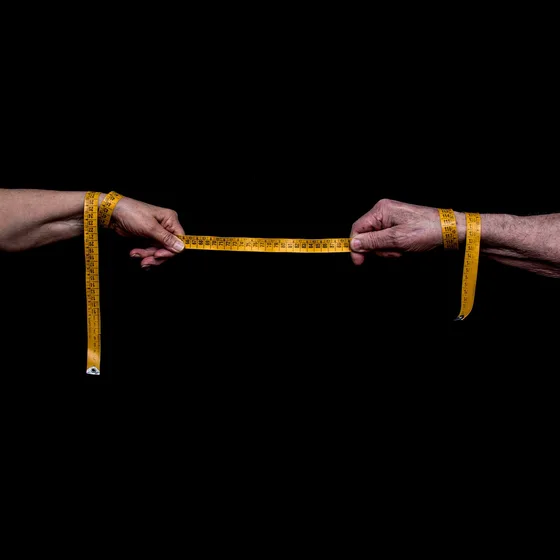 Deux mains tendent un mètre ruban jaune sur fond noir
