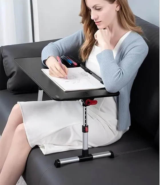 Femme assise sur un canapé qui écrit sur une table de lit réglable posée devant elle